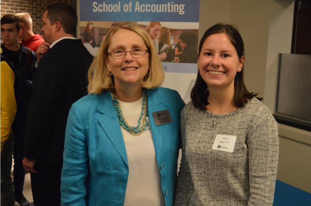 An alumna and a faculty member smile for a photo together at the Academic Major Fair.